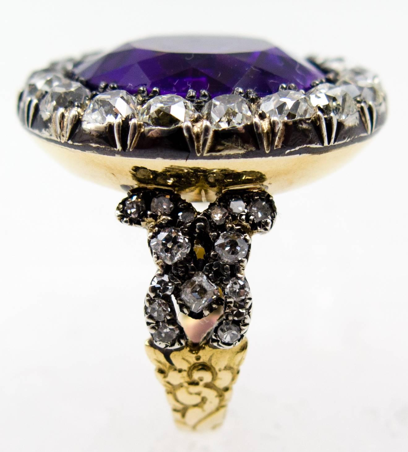 A unique and conversation-starting antique ring with a richly hued, royal purple round amethyst completely surrounded in a halo of chunky and sparkling old European cut diamonds sunk into silver topped gold, spanning a full inch in diameter across