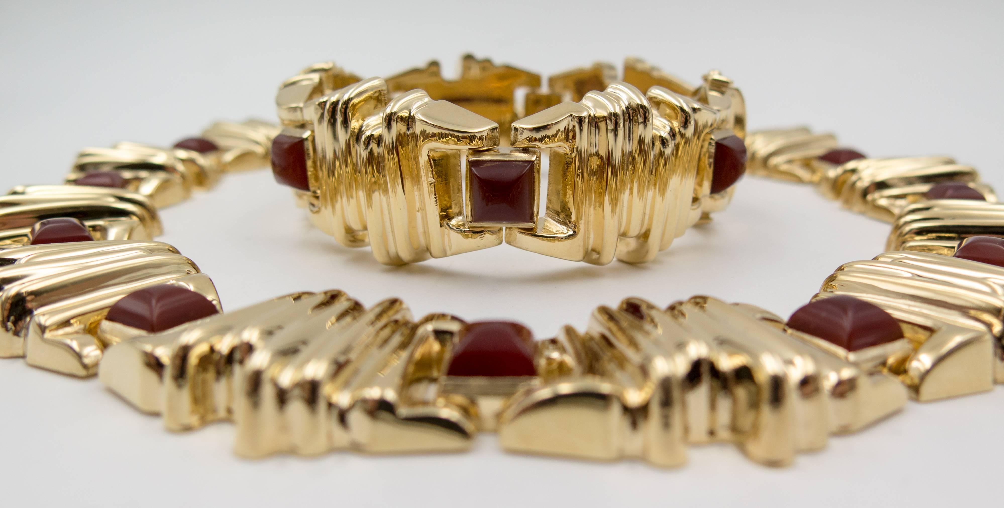 An elegant suite consisting of 14 karat gold geometric elements zigzagging around the neck to alternate with square sugarloaf cut (peaked in the center) rich reddish brown carnelian stones.  The interior diameter of the necklace is 17", which