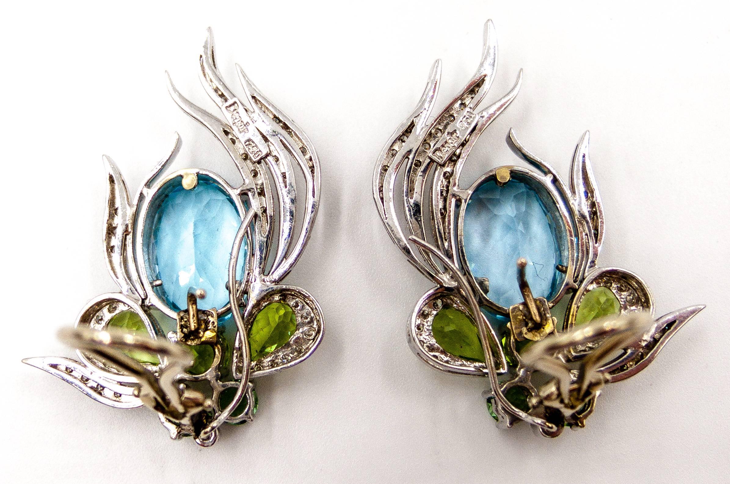 A flash of cool colors graces the ear in these lovely earclips. Large oval aqua toned blue topaz ovals are accented with shoulders of green peridot pearshapes and dots of pale green zircon at the base.  The colors are edged by graceful fronds of