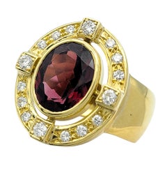 Anello con granato taglio ovale e diamanti a corona, con fascia larga in oro giallo 18 carati