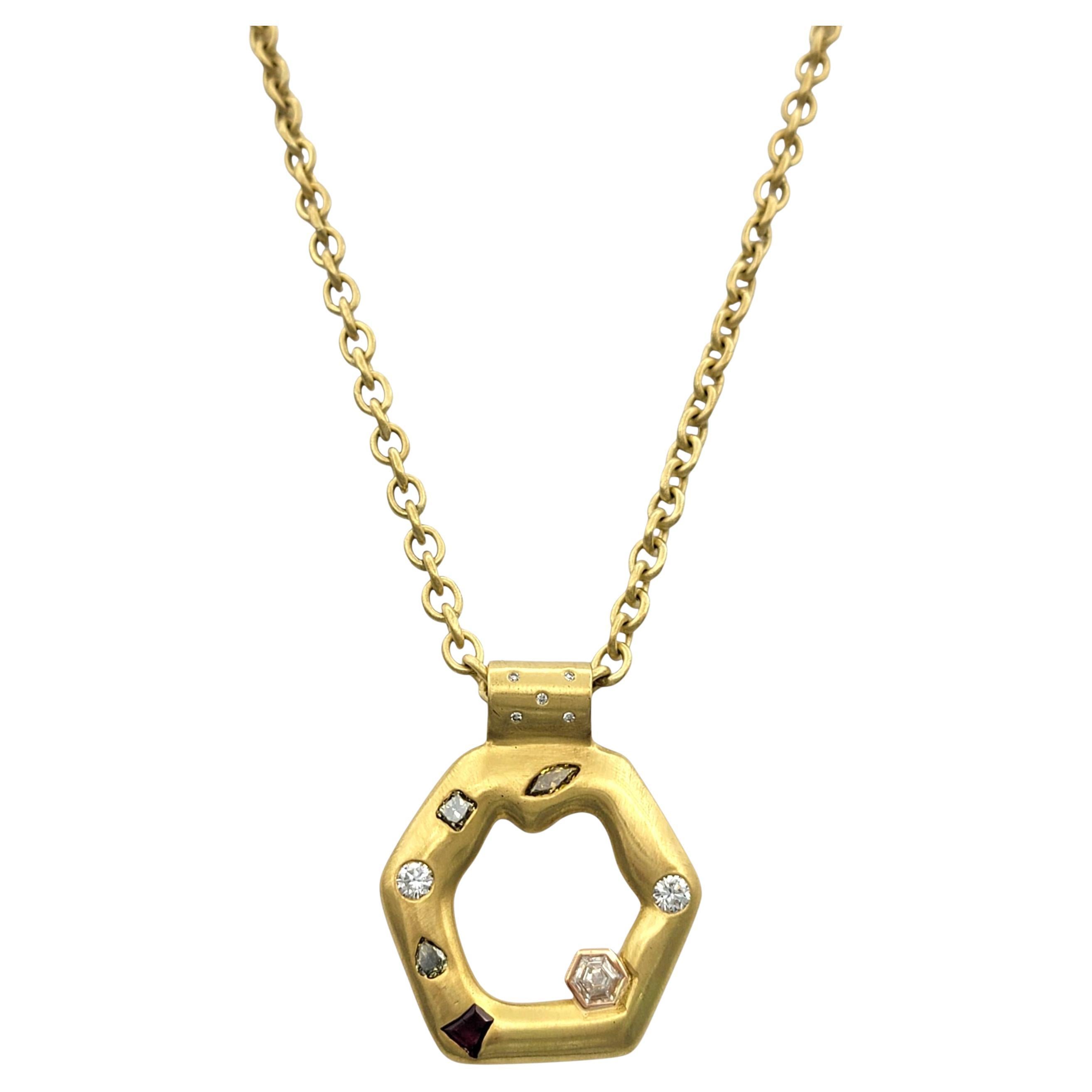 Questa audace e scultorea collana con ciondolo è realizzata in oro giallo 18 carati con finitura satinata e dettagli incisi che aggiungono una ricca texture. La forma esagonale del pendente è moderna e organica allo stesso tempo, incastonata