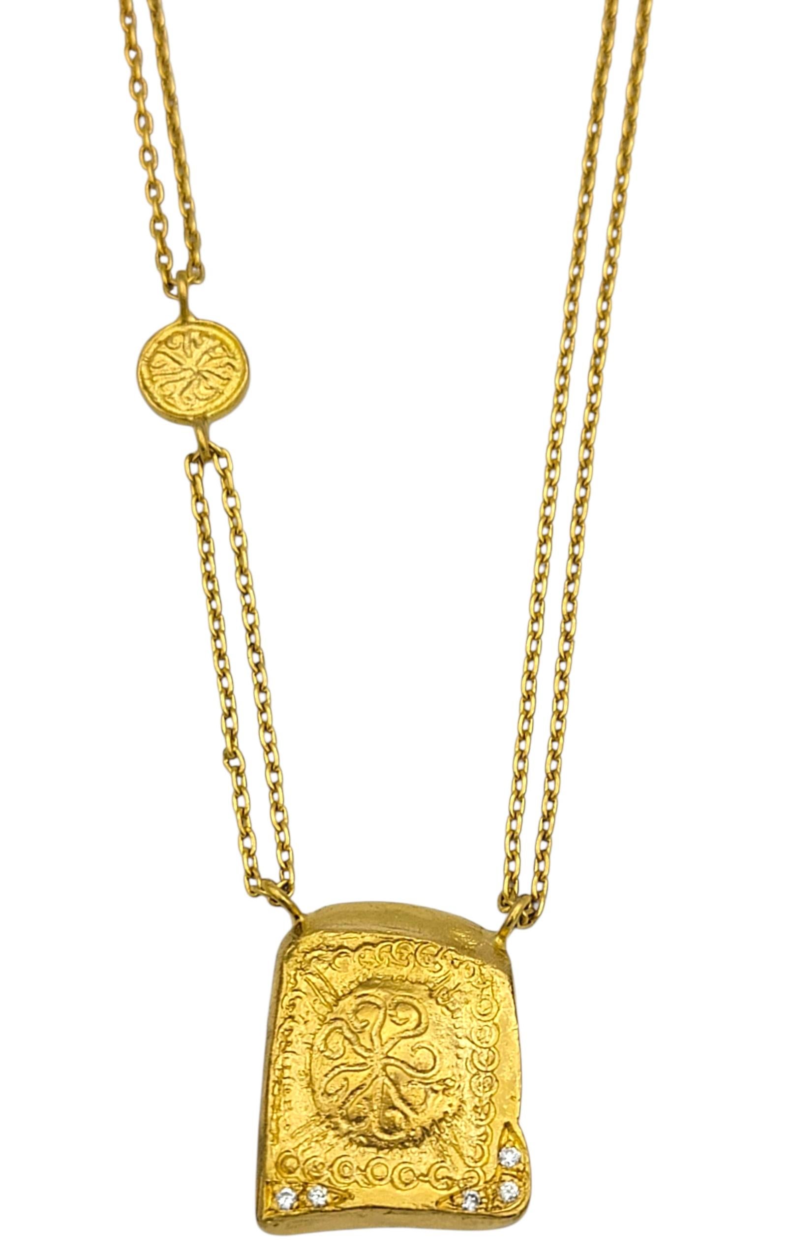 Ce collier richement détaillé est réalisé en or jaune 24 carats lumineux, avec une double chaîne qui mène à un pendentif sculptural en forme de tablette. La tablette est ornée de gravures complexes et de cinq diamants ronds de taille brillante qui
