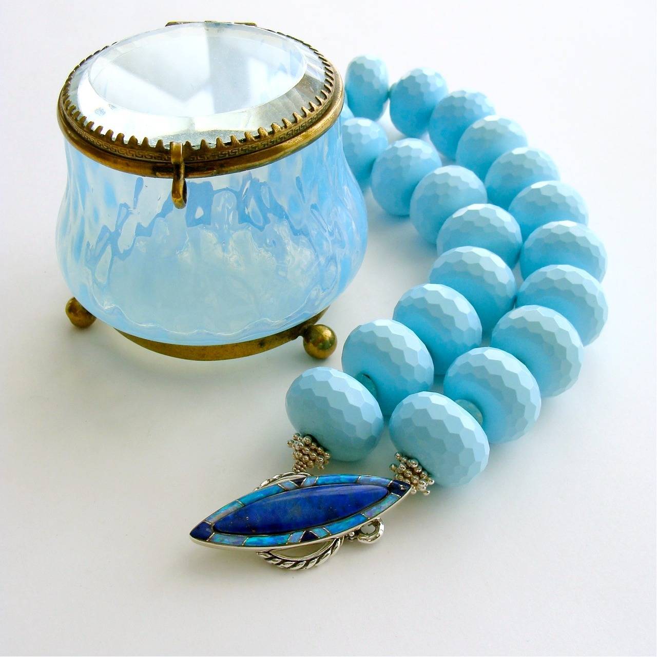 Highly-coveted honeycomb cut jumbo reconstituted turquoise rondelles have been separated by German cut Russian amazonite and are further enhanced with a luxurious marquise-shaped inlaid toggle clasp of lapis and opal.  The gorgeous sterling silver