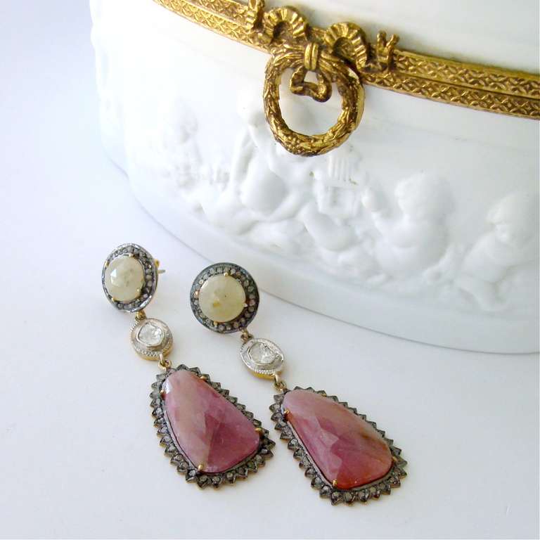 Sparkling faceted pink and ivory sapphire slices encircled by pave diamonds in a rhodium silver setting have created a classic and timeless pair of post style dangle earrings.  Whimsical and organic Polki diamonds have been juxtaposed between these