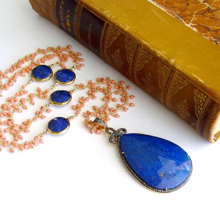 A delicate hand linked chain of pink peach coral is gently intercepted with beautiful faceted lapis connectors to complement the stunning lapis pendant freckled with gold and encircled with pave diamonds.  Poised at the top of the gorgeous lapis