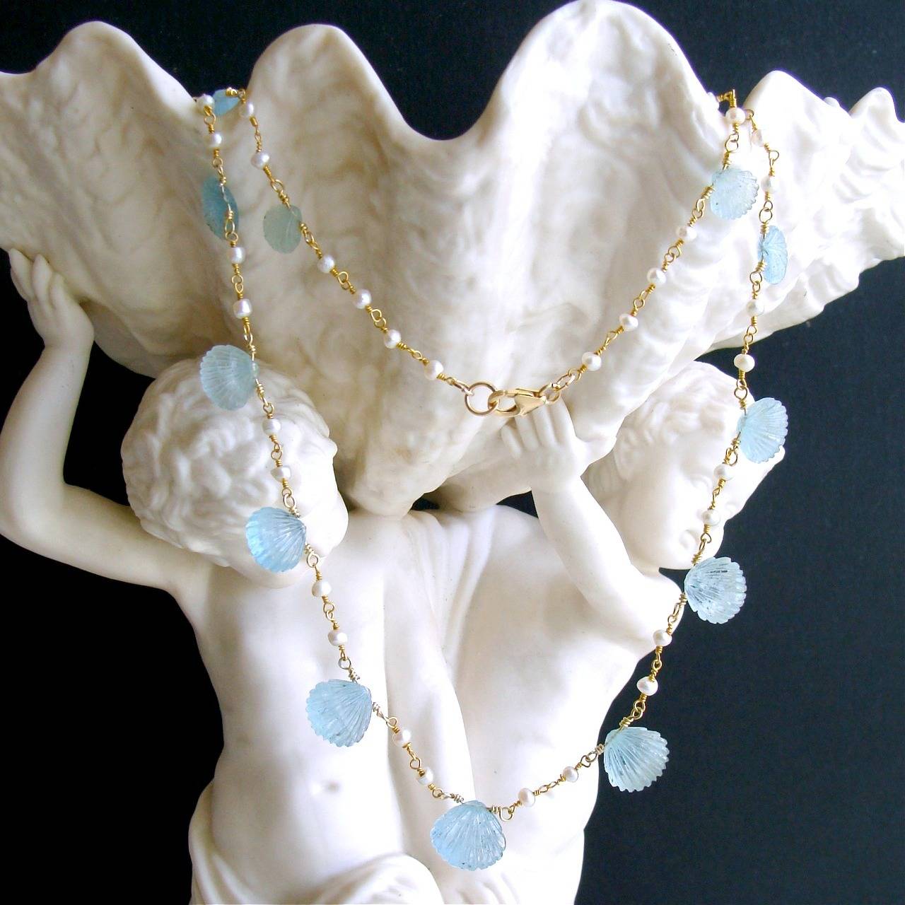 Les Coquilles de la Mer Necklace.

Hand carved graduated aquamarine shells have been delicately poised between diminutive freshwater seed pearls to create this charming ode to summer necklace.  The frothy colors of the aquamarine stones range from