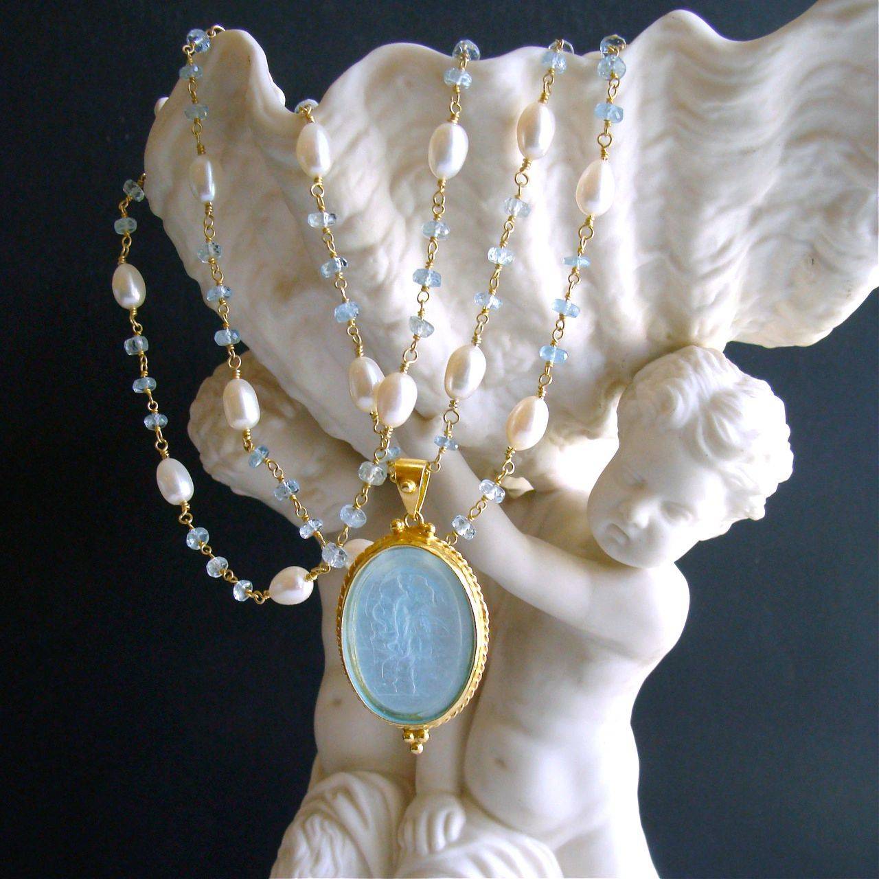 Matera Necklace.

A long delicate necklace of hand-linked frothy aquamarines and creamy freshwater pearls, is perfectly coordinated with the powdery aqua color of a Venetian glass intaglio cameo pendant.  The subject of the cameo intaglio is a
