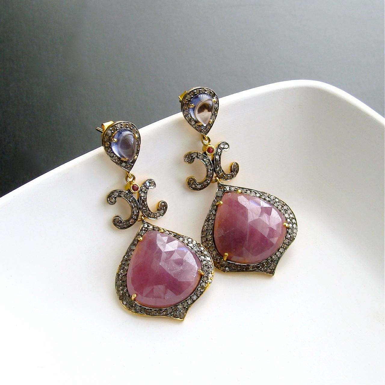 Raspberry Pink Violet Sapphire Diamond Earrings - Candace Earrings.

Ravishing raspberry pink faceted teardrop sapphires, surrounded by a Moorish shaped pave setting of sparkling diamonds in mixed metals, is the focal point of these gorgeous