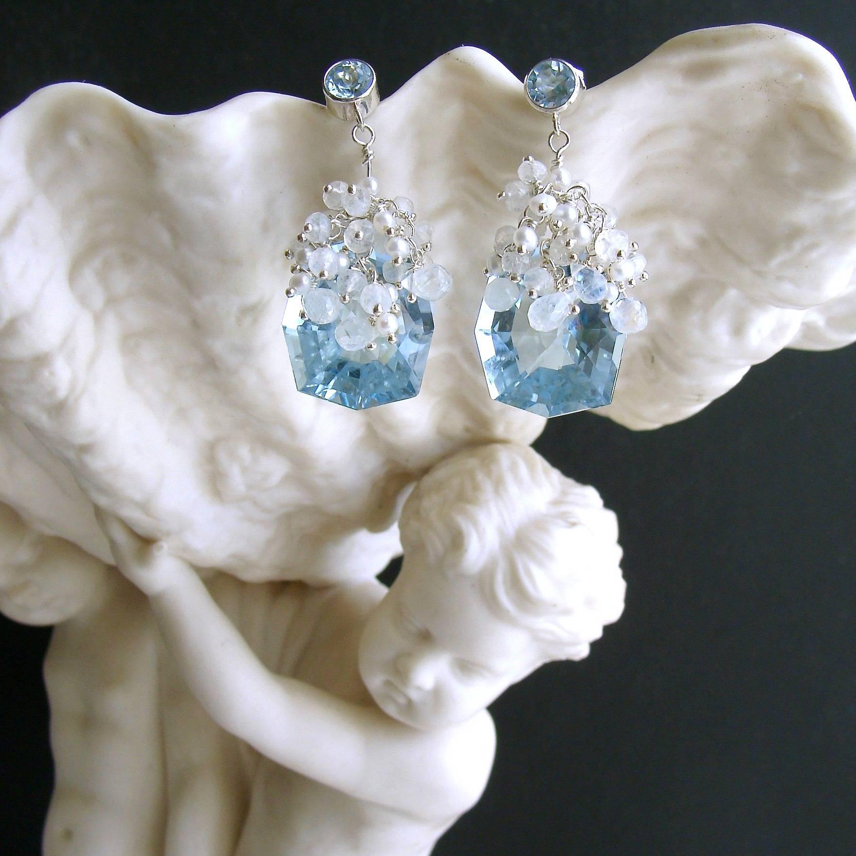 Sparkling fancy-cut blue topaz have been adorned with cascading tendrils of hand-linked minuscule seed pearls and flashy moonstone rondelles and briolettes, while suspended from simple blue topaz post earrings.  The delicate nature of these earrings