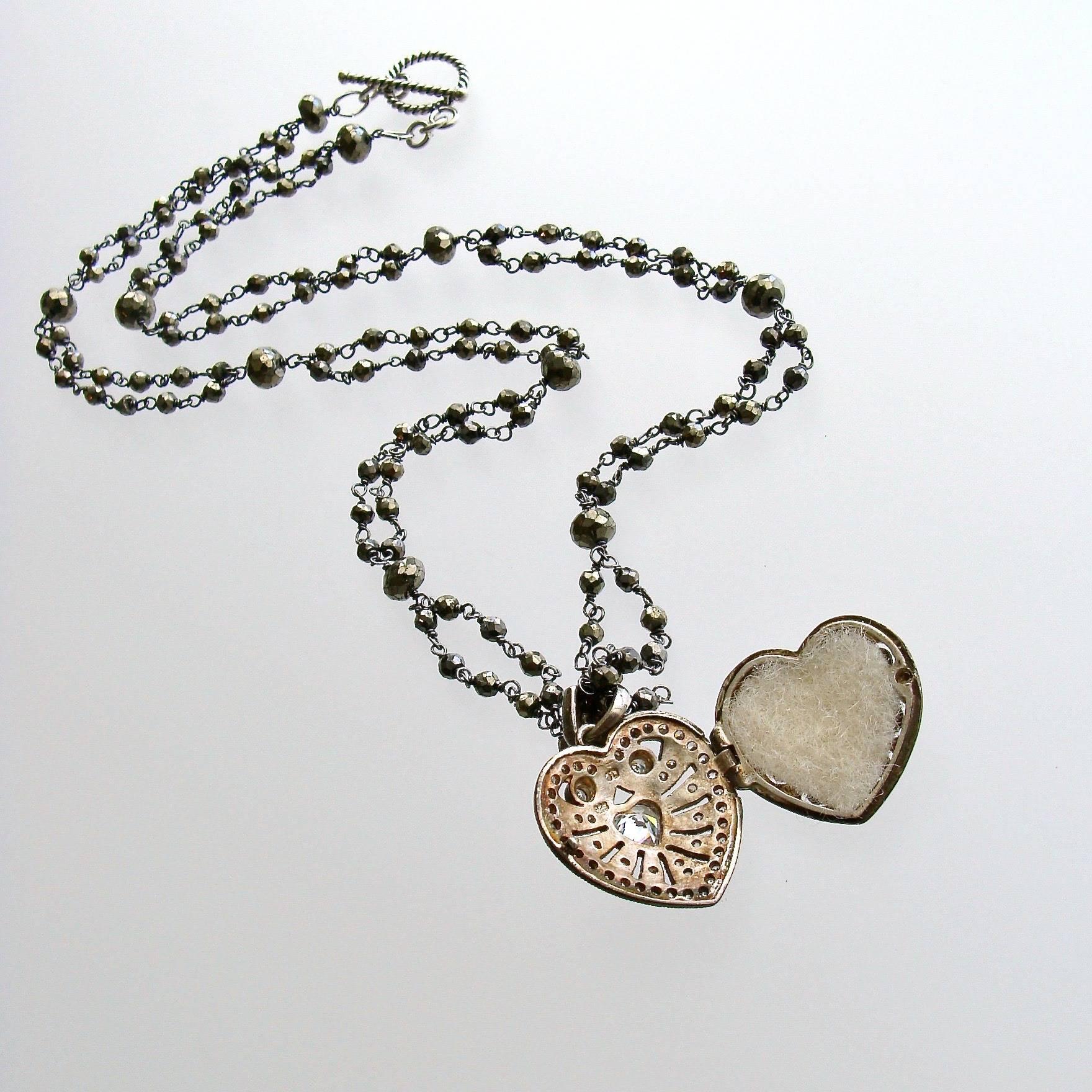 Saint Esprit II Heart Necklace.

A double strand of hand linked pyrite with a Victorian silver paste heart vinaigrette is paired with other layering necklaces revolving around the French theme of the Saint Esprit Dove.  The darling little heart