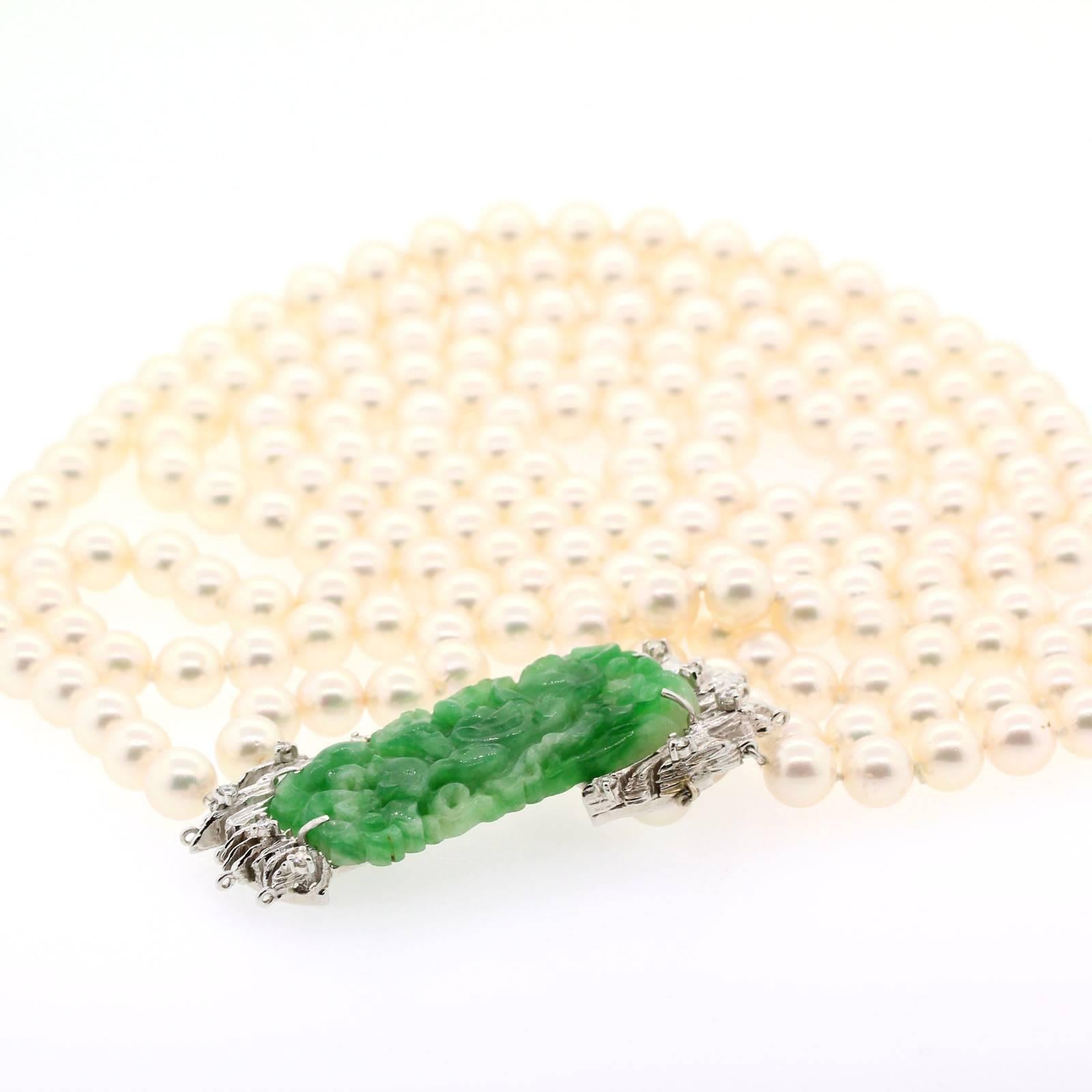 A beautiful rectangular green Jadeite, carved with floral and organic motif in relief with open pierce work set in 14 Kt white gold and accented with Round Brilliant Cut Diamonds.  The Jadeite is suspended from a double strand of white Pearls. 