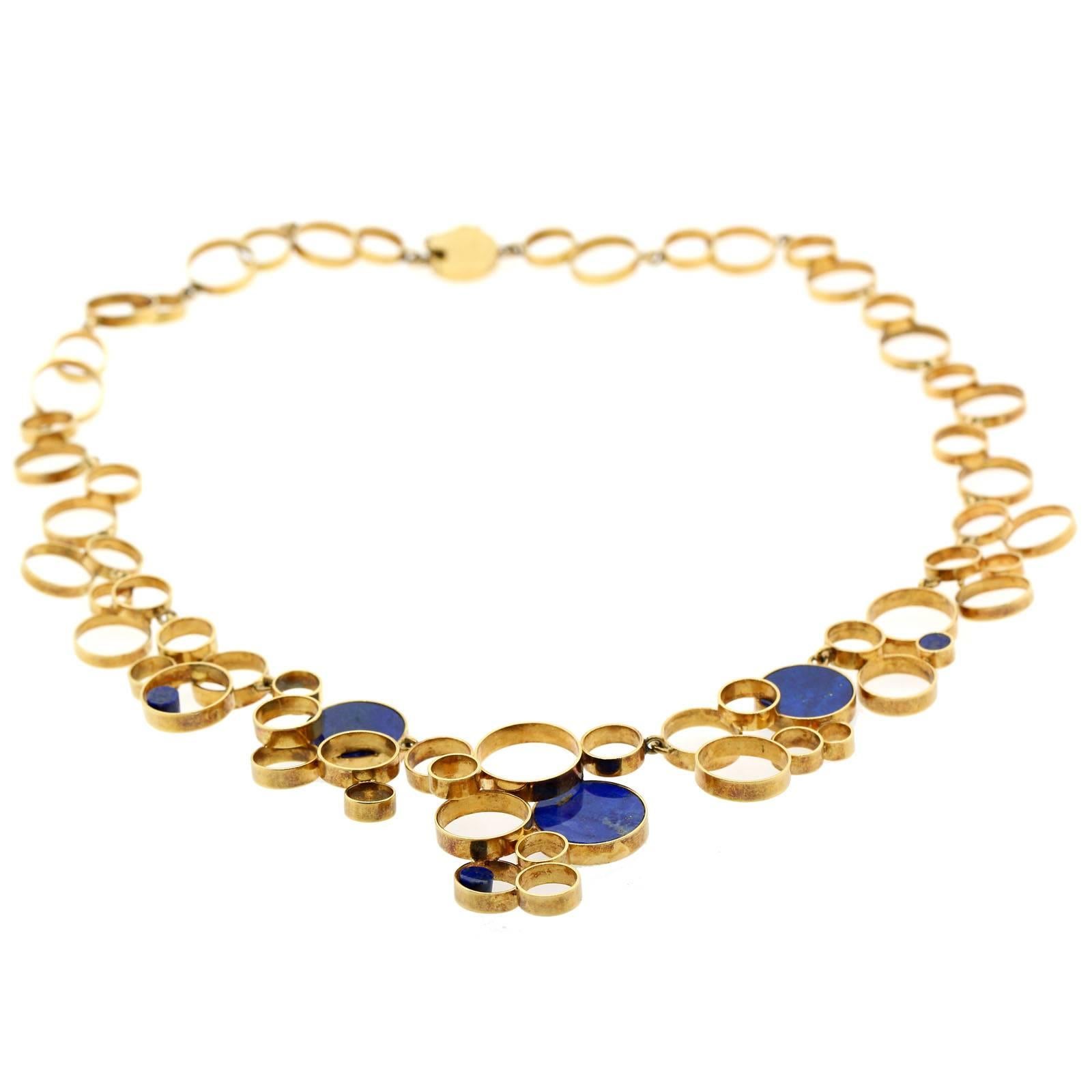 A through back to the 1960s, artistic necklace of numerous open circle disks of various sizes resembling floating bubble.  The necklace is accented with three large and three small Lapis Lazuli plaques. 