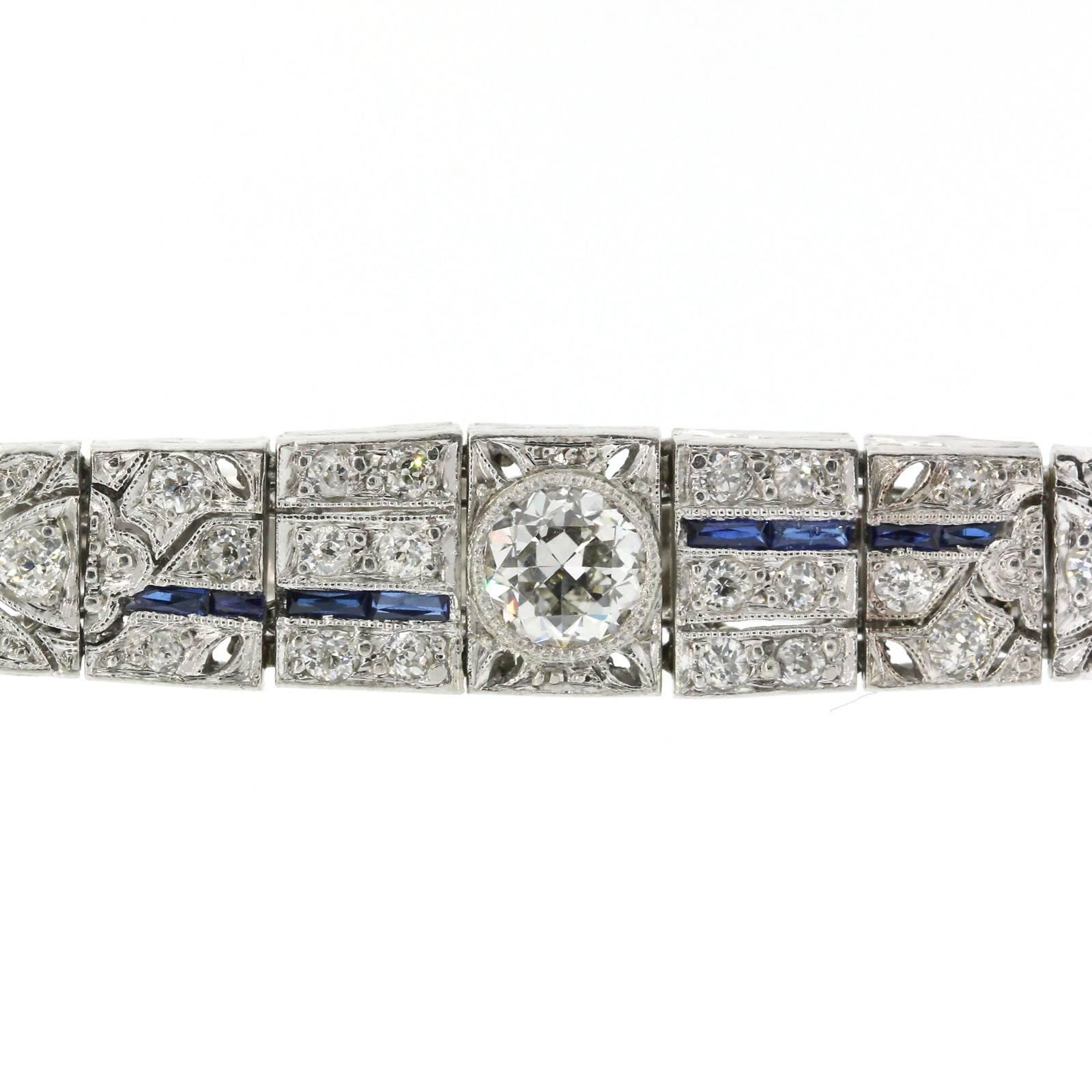 Coveted tapered Art Deco bracelet of box designed links and open work, featuring a bezel set Old Cut Diamond in center, and flashing over three carats of Old European Cut Diamonds. The delicate design work is accented with original synthetic