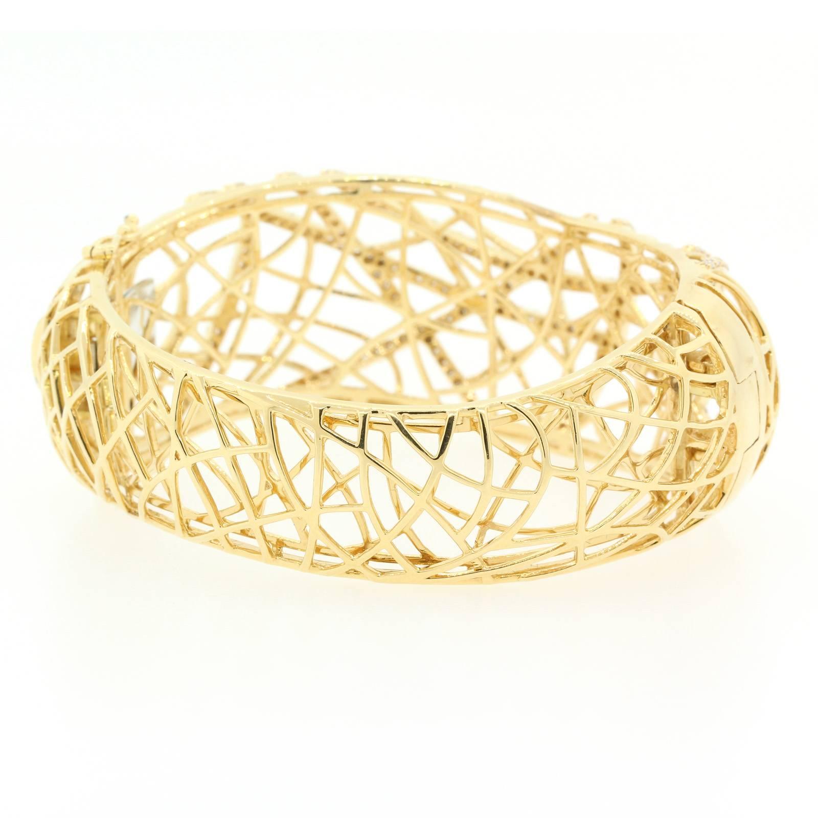 A beautifully designed free form open work bangle-bracelet fabricated in 18KT yellow gold.  The top  is accented with three carats of sparkly Round Brilliant Cut Diamonds, set in five swooping lines.  Circa 1990s. 