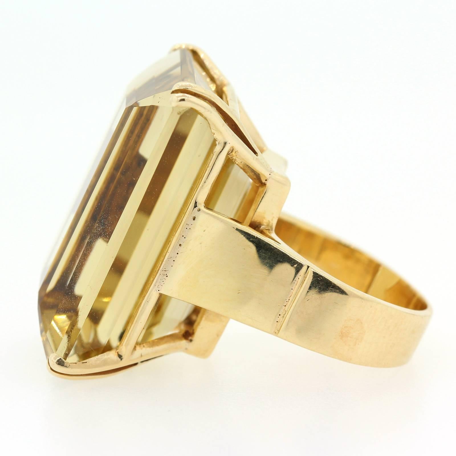 A strong statement projection from this 1950s large Citrine 14KT yellow gold ring.  The Emerald Cut Citrine weighs approximately seventy carat is beautifully presented on a four fluted prong double wire basket.   Pretty exceptional large ring!