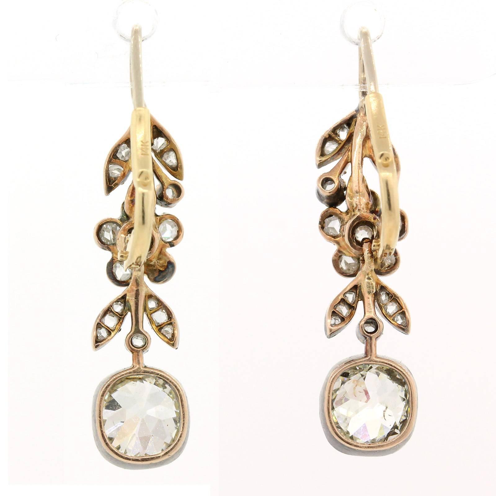 Elegantly understated 1890 pair of Silver top 14KT yellow gold earrings.  The diamond floral tops each dangles an old Cushion Cut bezel set Diamond, the two diamonds weigh 2.05 carat of I/J color - VS/SI clarity.   Old European & Rose Cut
