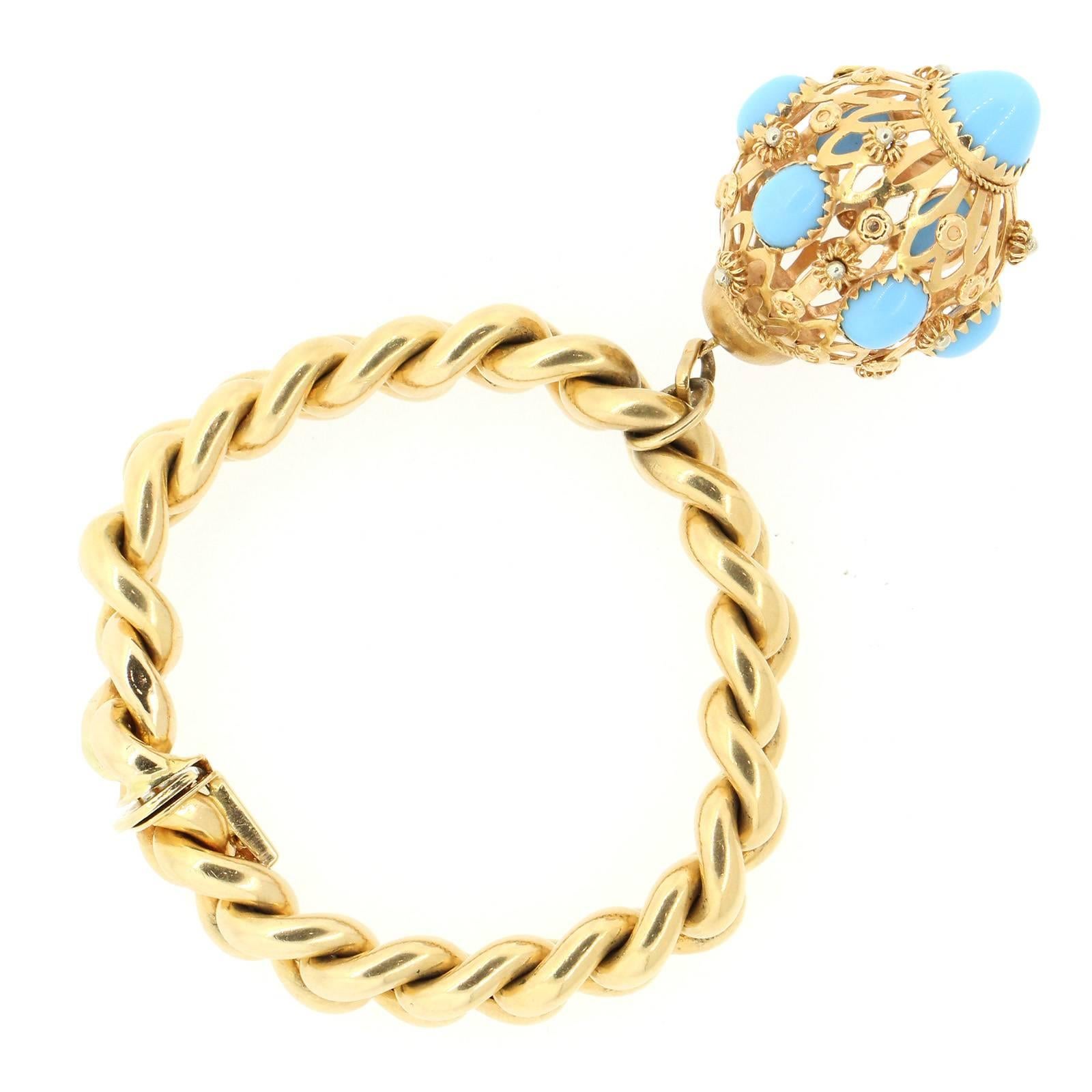 A playful 18KT yellow gold bracelet featuring an open work pomander like 18KT charm bezel set with seven cabochon cut blue stones.  The bracelet is seven inches long and is marked with Italian hallmarks.  Circa 1960s