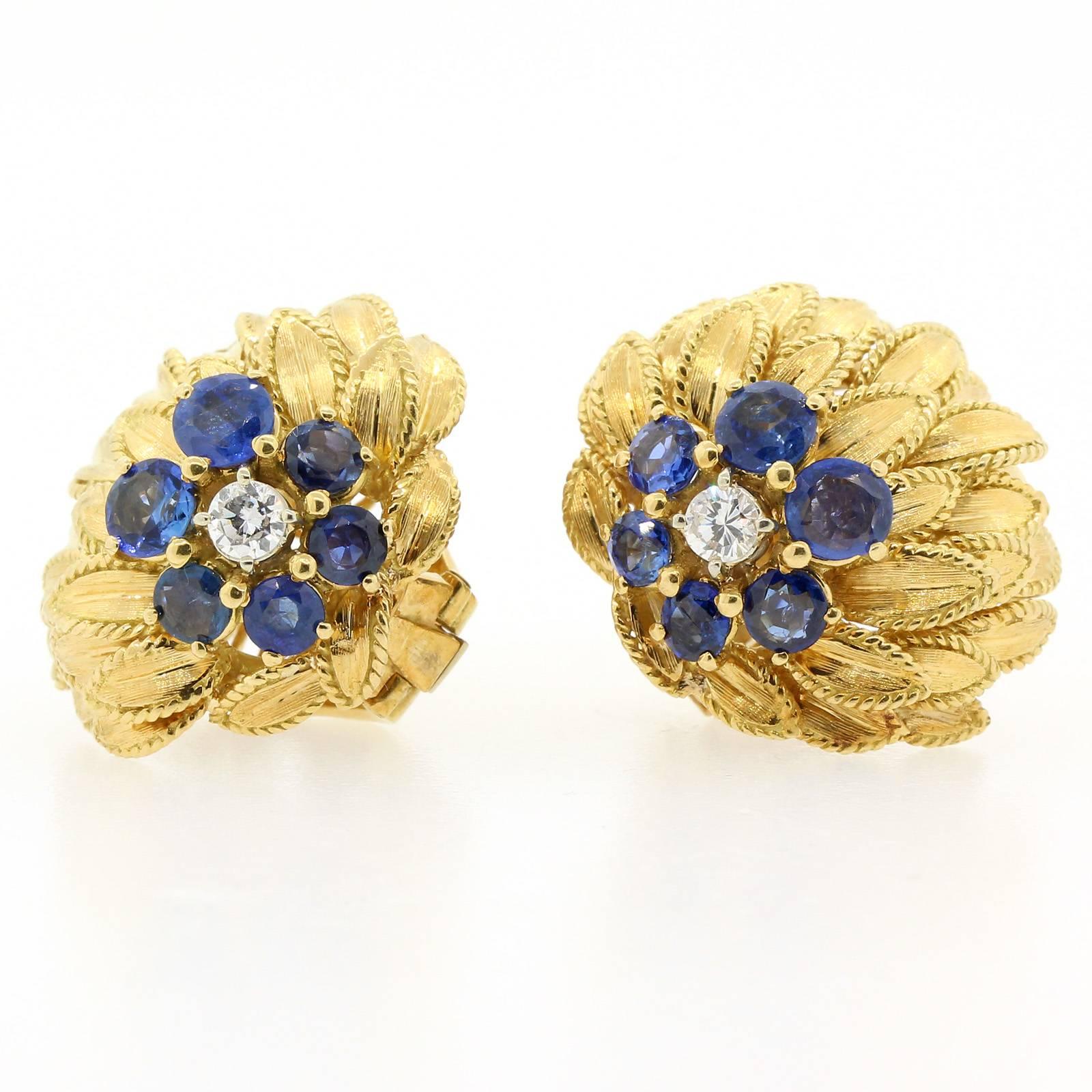 Vintage Sapphire & Diamond Earrings.  The earrings are fabricated in 18KT yellow gold as  a cluster of overlapping  leaves.  Each centering a pistil of one Round Brilliant Cut Diamond surrounded by seven Round Blue Ceylon Sapphires.  All