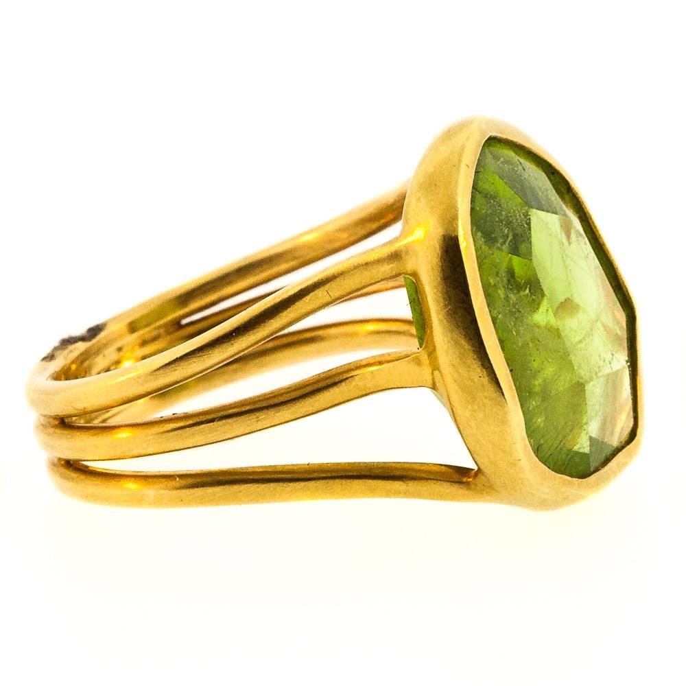 An artisan hand made ring featuring a 12.75 carat free form Peridot gemstone, bezel set in 18KT yellow gold.  The three wire strand band adds to the uniqueness of this truly fashionable ring.  It is a sizable 7.5.  Fab! 