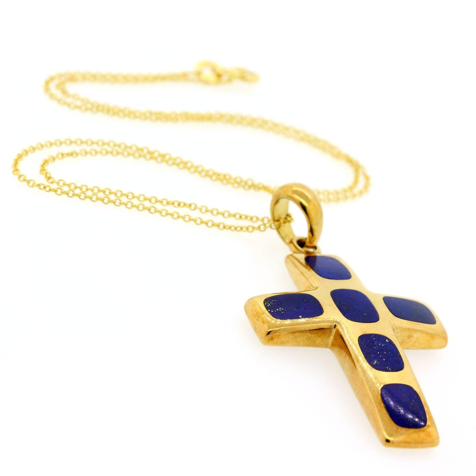 A beautiful 1970s Italian 18KT yellow gold cross with six cushion shape inlaid Lapis Lazuli stones. The cross is suspended from a 14KT yellow gold 16 inch box link chain, and measures 2 inches high by 1 1/8 inches wide.  The bail is stamped 