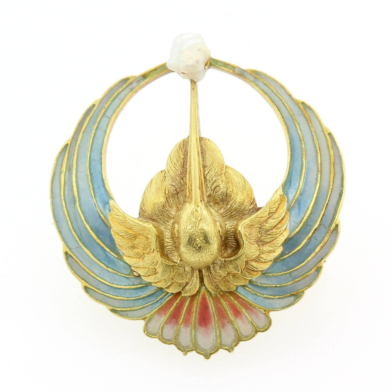 A unique  Art Nouveau Plique-a-Jour  brooch fabricated in 18KT yellow gold featuring a stork with spread out  wings that fan out in variegated plique-a-jour.  The beak is holding a natural Mississippi mud Pearl.  Circa 1900s.