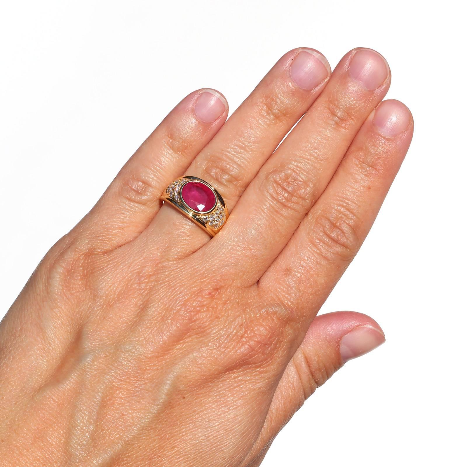 A bold 18KT yellow gold ring featuring a bezel set oval Burma heated Ruby weighing 2.09 carats.  The half dome setting is accented with 0.55 carat of Round Brilliant Cut Diamonds.  The ring has great character!