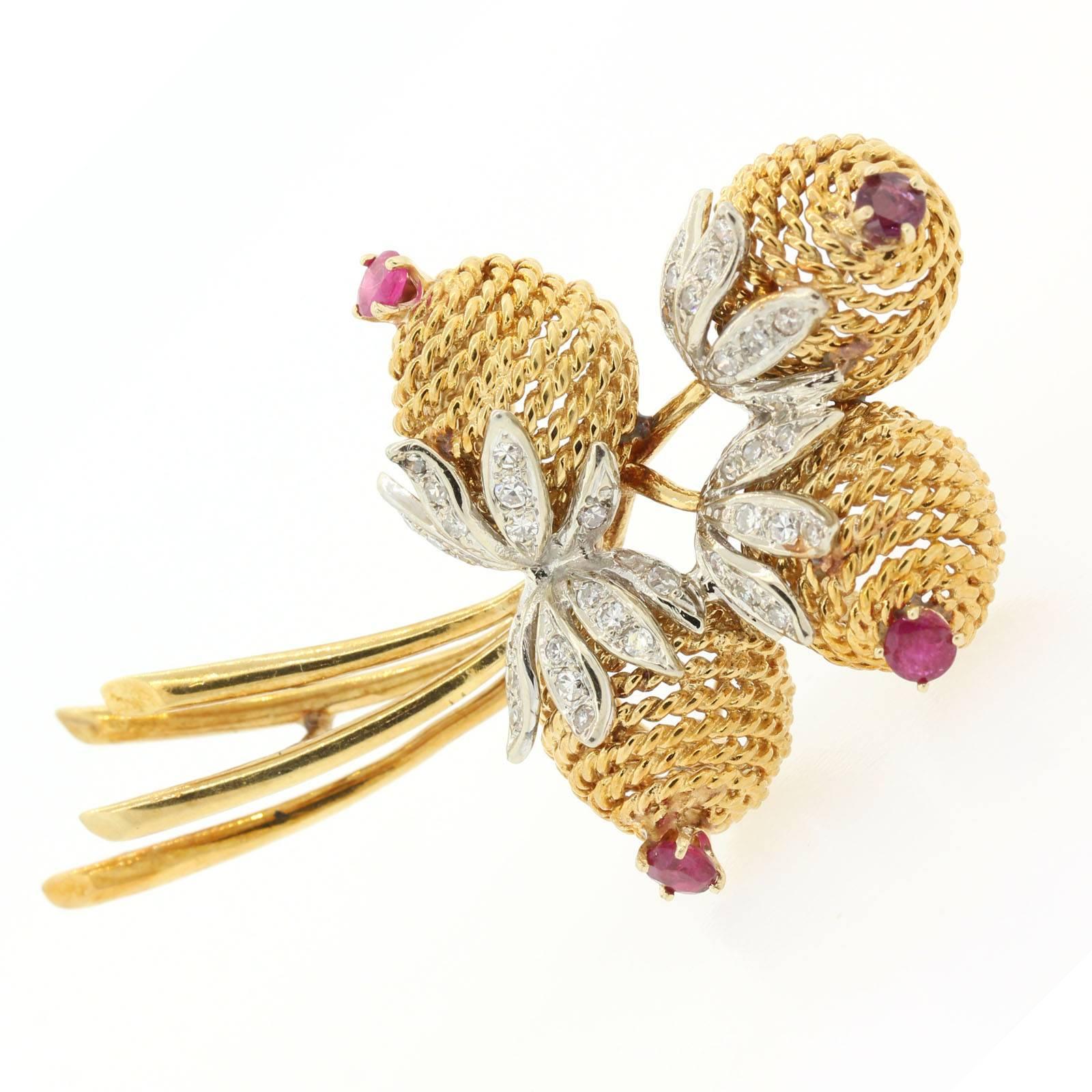 Vintage 1970s Cartier 18KT yellow gold bouquet brooch.  The brooch features four stylized flowers blooming from 18KT white gold diamond petals, and each flower is accented with a round cut Burma Ruby, the four weighing 0.65 carat.  The diamonds all