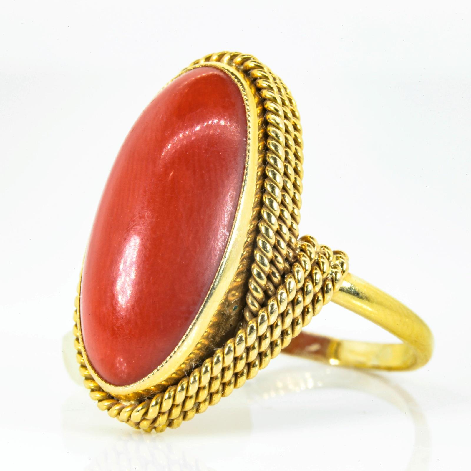 A very nice handmade 1960s oval cut Coral ring, fabricated in 18KT yellow gold.  The setting is enhanced with a triple rope like design surrounding this beautiful Coral which measures 21.65 x 10.80 x 5.19 mm.  The ring is a sizable 9 and it is