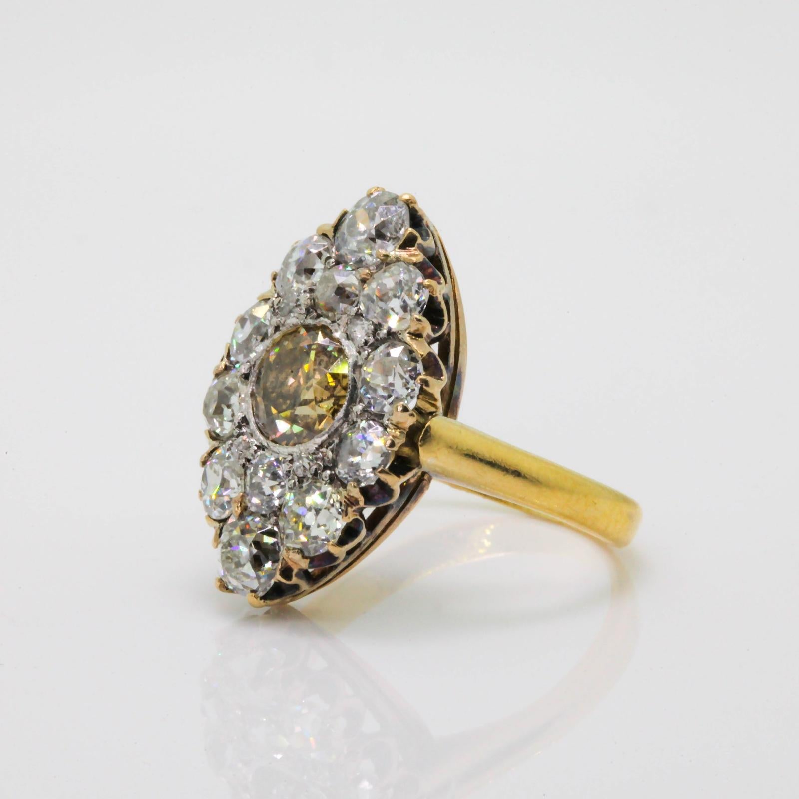 A unique marquise shape platinum and 18KT yellow gold ring.  The center features a 0.87 carat natural champagne color Old European Cut Diamond of SI3 clarity, surrounded by a medley of twelve Old Mine and Old European cut diamonds.  The total weigh