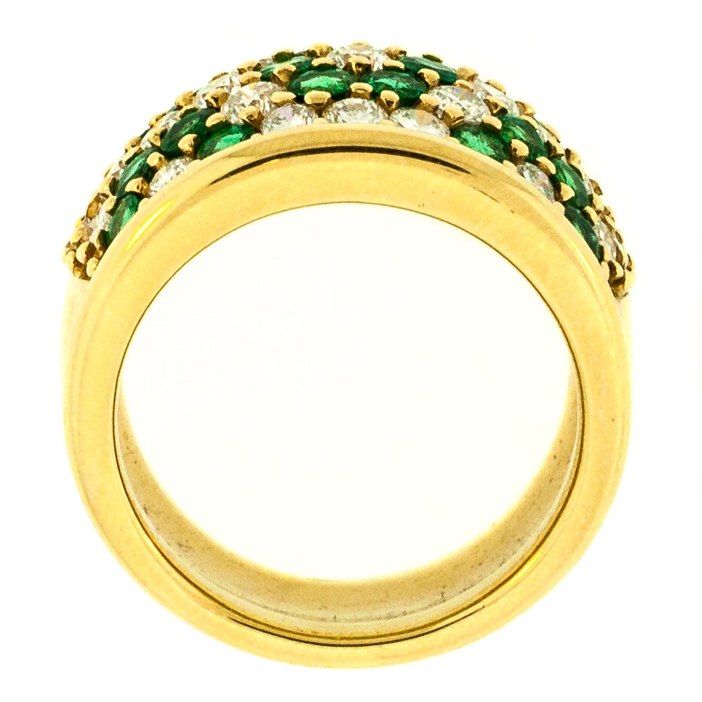 Emerald and Diamond Floral Cluster Ring is made from 14 KT Yellow Gold. A brilliant design, this piece is vibrant, colorful, and fun. Highlighted are 27 Round Brilliant Cut Diamonds and 22 round Colombian Emeralds set in a floral cluster