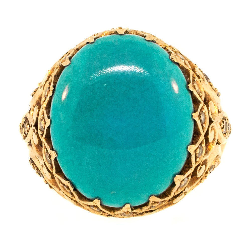 Turkish inspired Oval Cut Turquoise is set in a stunning 18 KT Yellow Gold open work mounting. Displaying a classic Dome Design, the mineral-rich gem is accented with Single Cut Diamonds. Like the waves of a Mediterranean Sea, this ring glistens