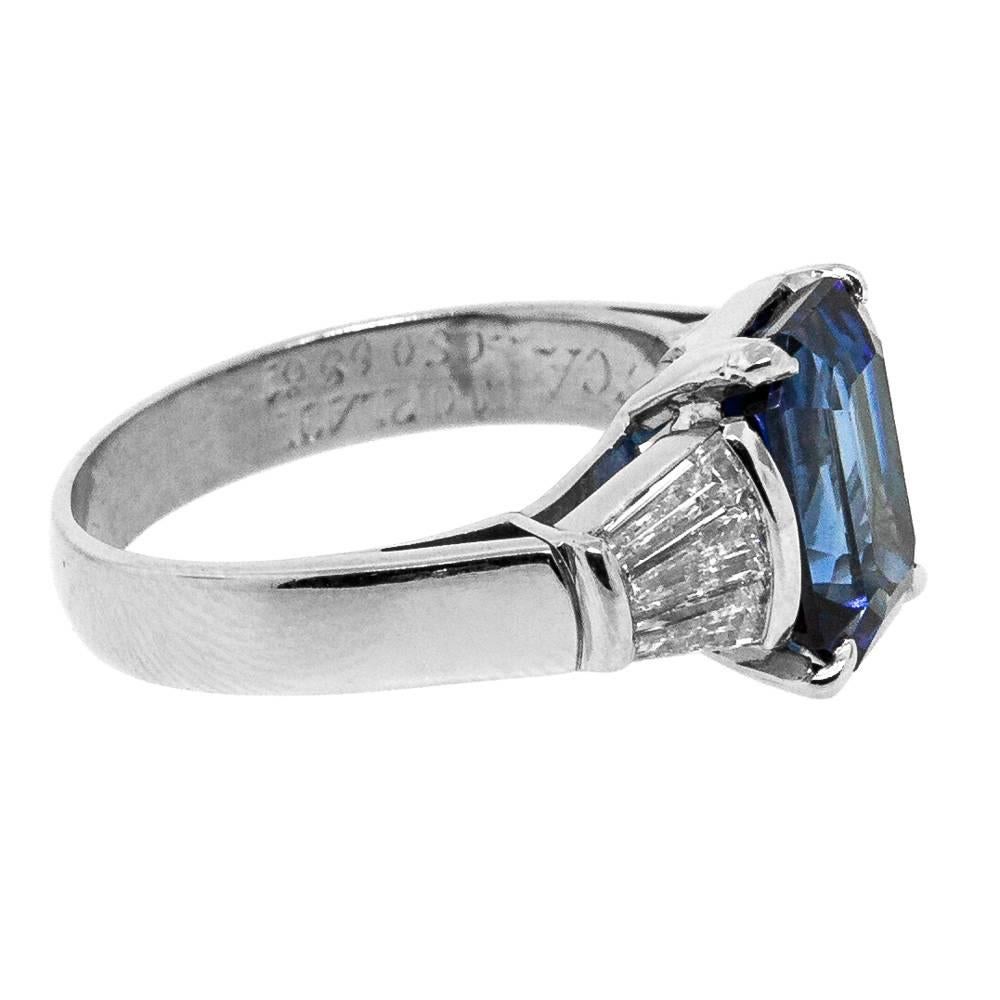 Impressive striking rectangular Emerald Cut Ceylon Sapphire A.G.L. certified the stone is standard heated with a color stability: Excelent. The Sapphire is set in a double wire four prong basket and flanked on each side by three Baguette Cut