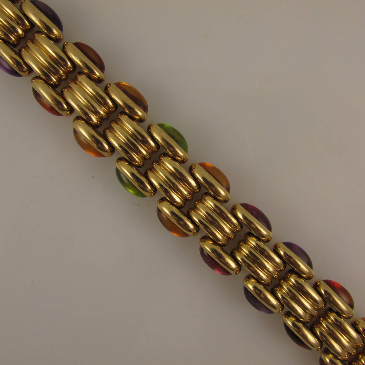 18KT yellow gold bracelet bezel-set with 19 oval cabochon semi-precious colored stones along each side, 38 stones total.

Signed Bvlgari, piece # BA15370. Bulgari no longer makes this bracelet.