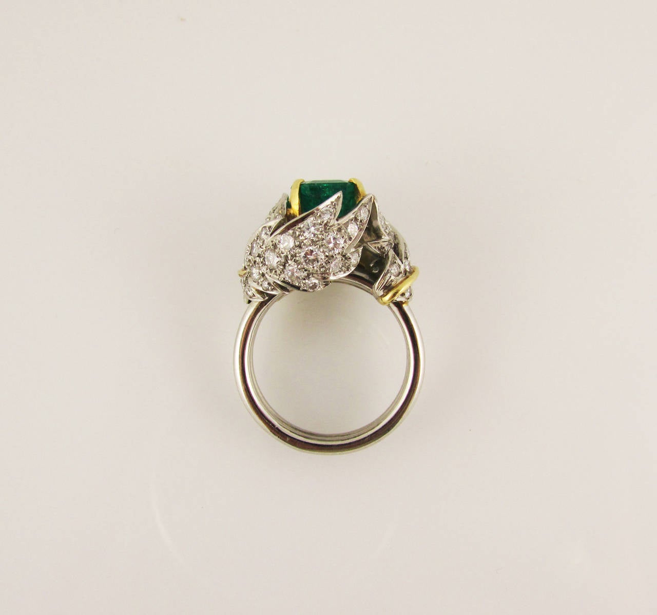 18KT white and yellow gold ring set at the center with an emerald-cut emerald estimated to weigh 3.35ct, wrapped in diamond pave leaves with yellow gold veins. Finger size 6.5.

Signed 