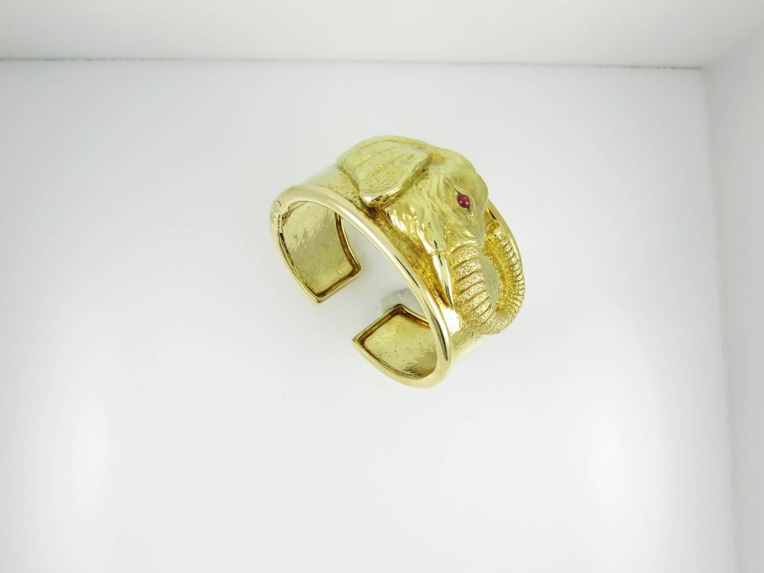 18KT yellow gold repoussé hinged cuff depicting the head of an elephant with a cabochon ruby eye. Circa 1970s.   
Signed WEBB  for David Webb.

Current retail price is approximately $39,000.