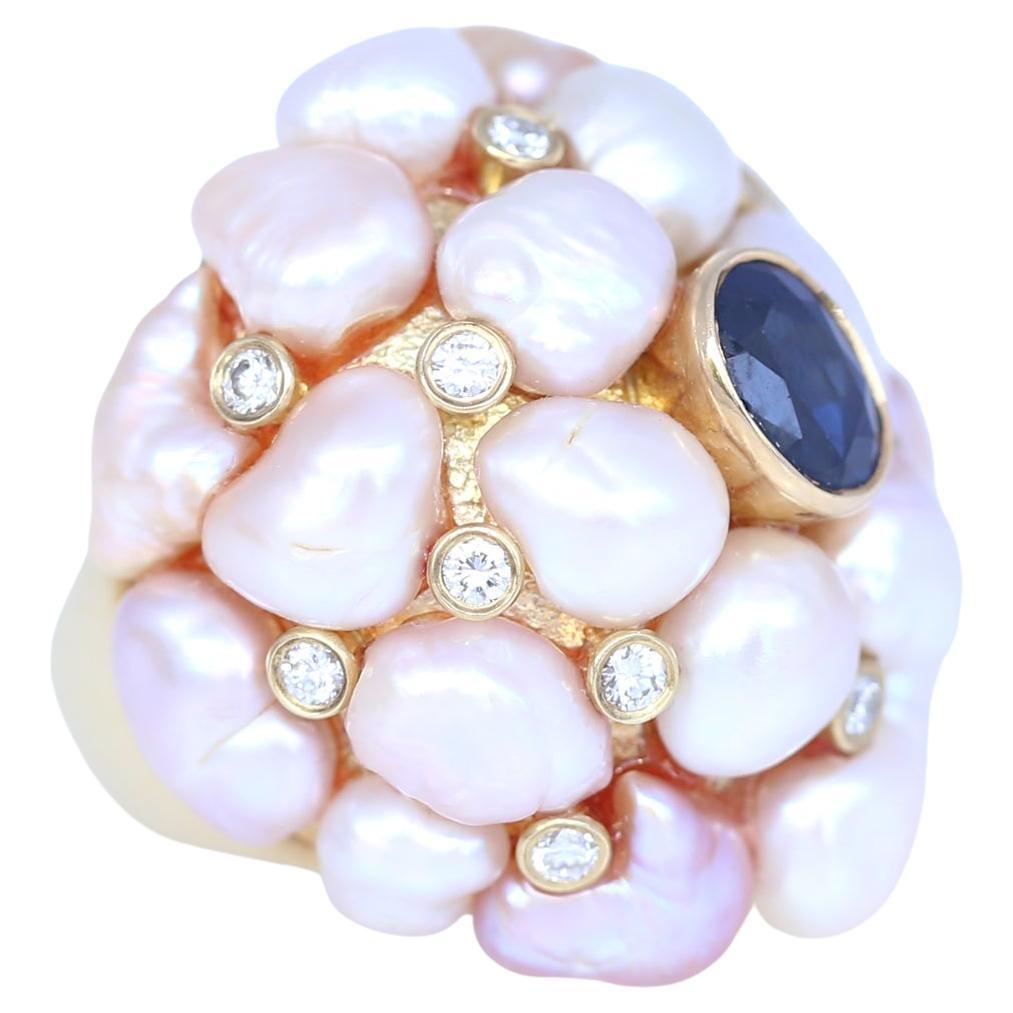 Fine Pearls of different shapes and Fine Diamonds are put together on top of a 14K Yellow Gold ring. With a fine deep blue Sapphire in the middle. Very bold and unmistakably 70-es design. 
Now sustainability is gaining momentum in the jewelery