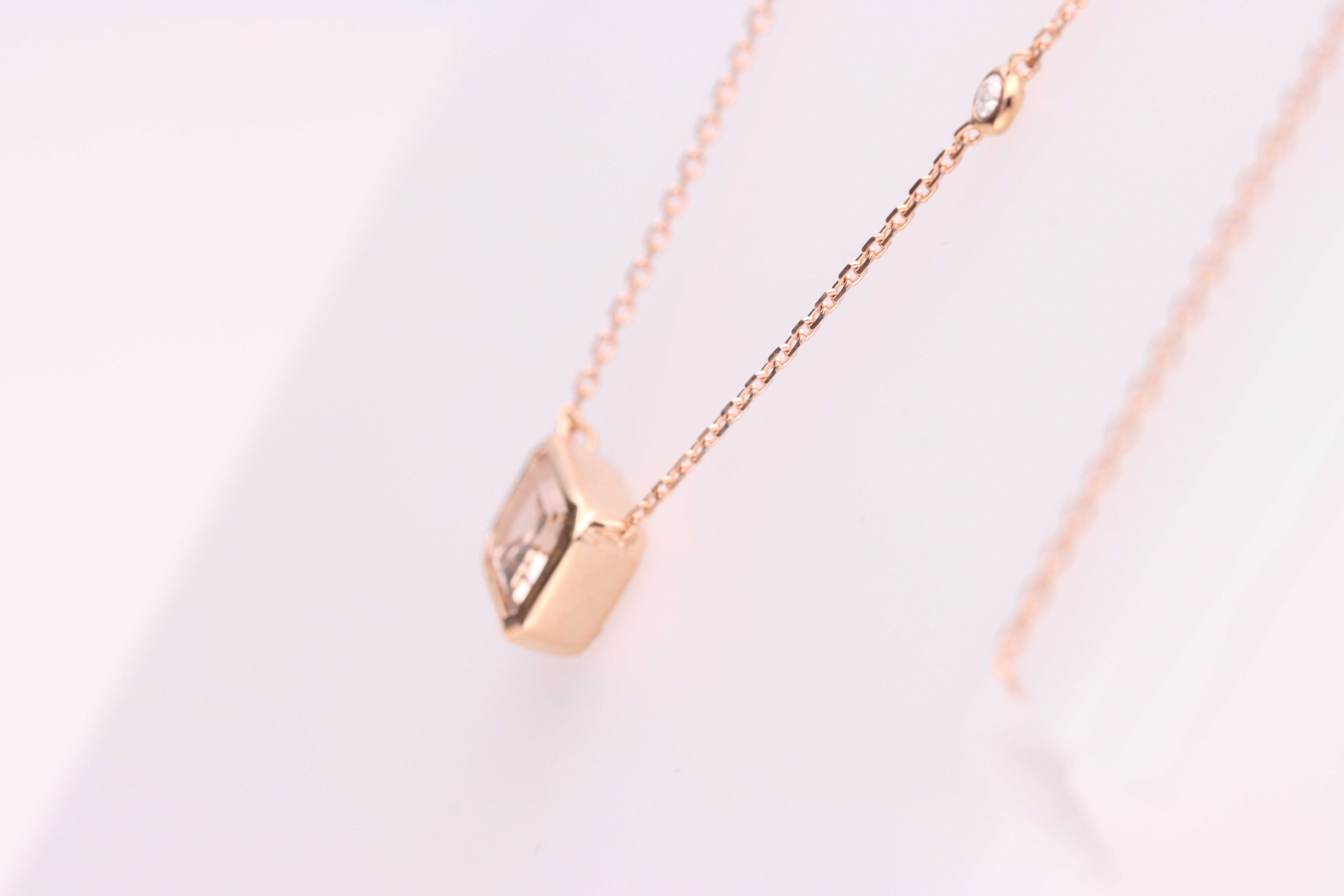 Ce collier minimaliste mais élégant est orné d'une magnifique Morganite en cristal clair de 1,5 carat, taillée en émeraude et sertie dans un élégant chaton en or rose 14 carats. Suspendue à une délicate chaîne en or ornée de deux diamants de chaque