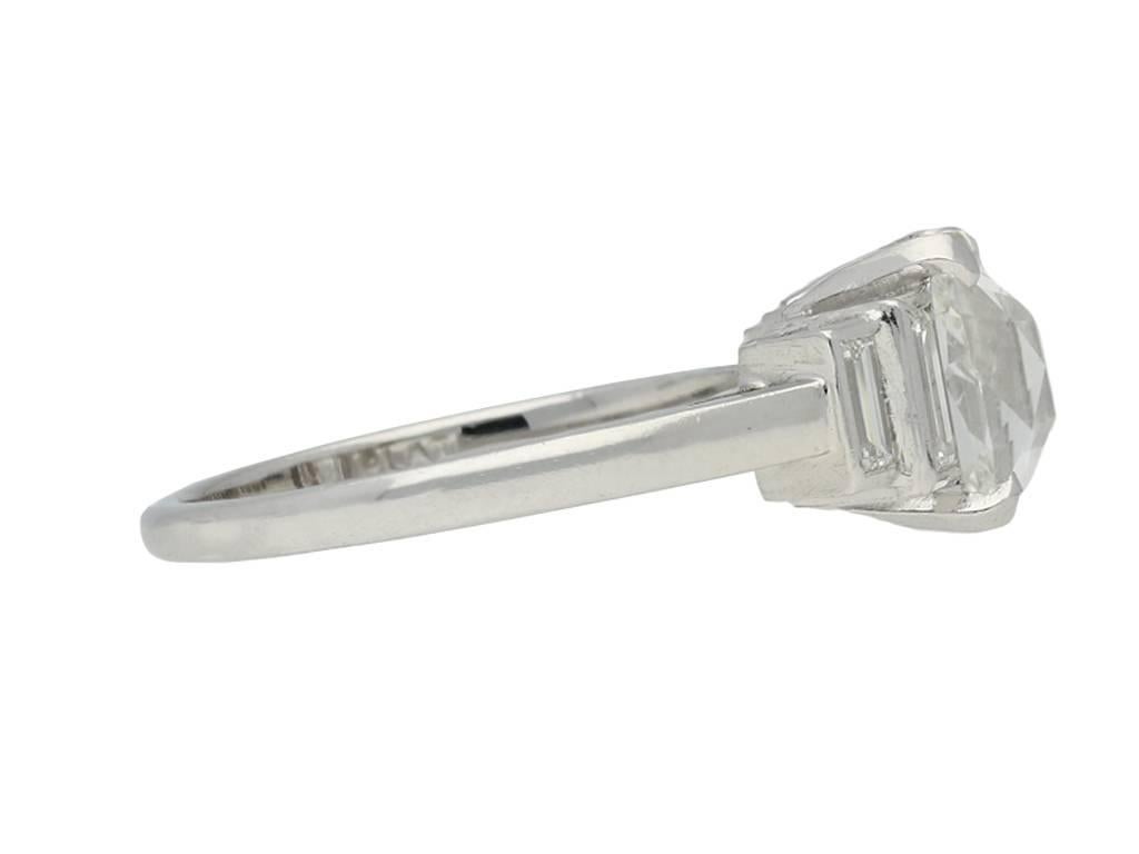 Art Deco solitaire diamond ring. Set to centre with one cushion shape old mine diamond, E colour, SI1 clarity with a weight of 2.06 carats, in an open back claw setting, flanked by four rectangular baguette cut diamonds in open back rubover settings
