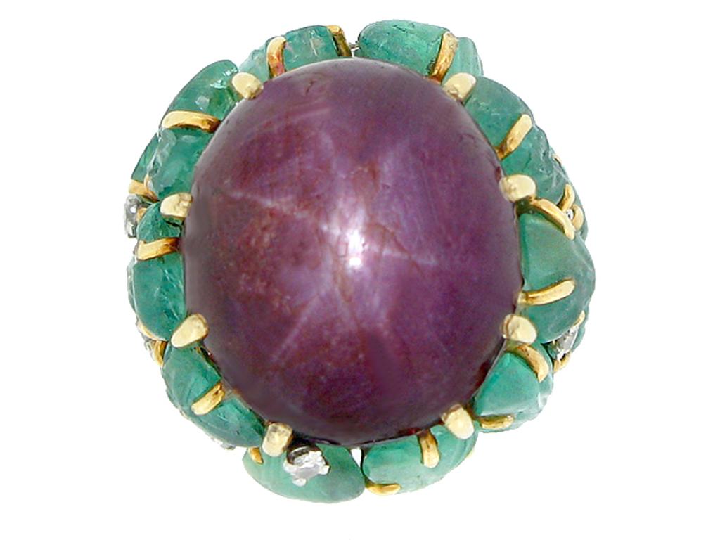 Anillo estrella rubí tallado esmeralda y diamante. Engastado con un rubí estrella cabujón ovalado natural sin realzar que muestra un fuerte asterismo con un peso aproximado de 30,00 quilates en un engaste de garras abierto por detrás, rodeado por un