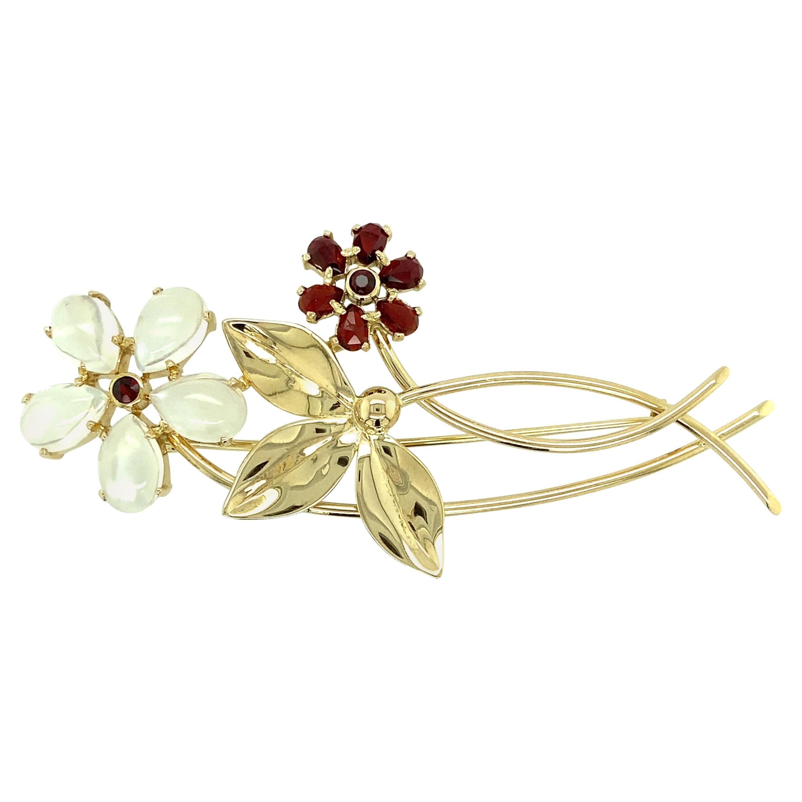One 14 karat yellow gold Tiffany & Co. flower pin set with five 11.45x6.80mm moonstones and eight garnets.  The pin measures 3 inches long, 1.5 inches wide and is complete with a traditional pin closure. 13.85 grams total.  