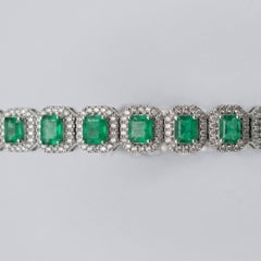 Bracelet « tennis » en or blanc 18 carats, serti d'émeraudes et de diamants en halo, d'un poids total de 12,50 carats