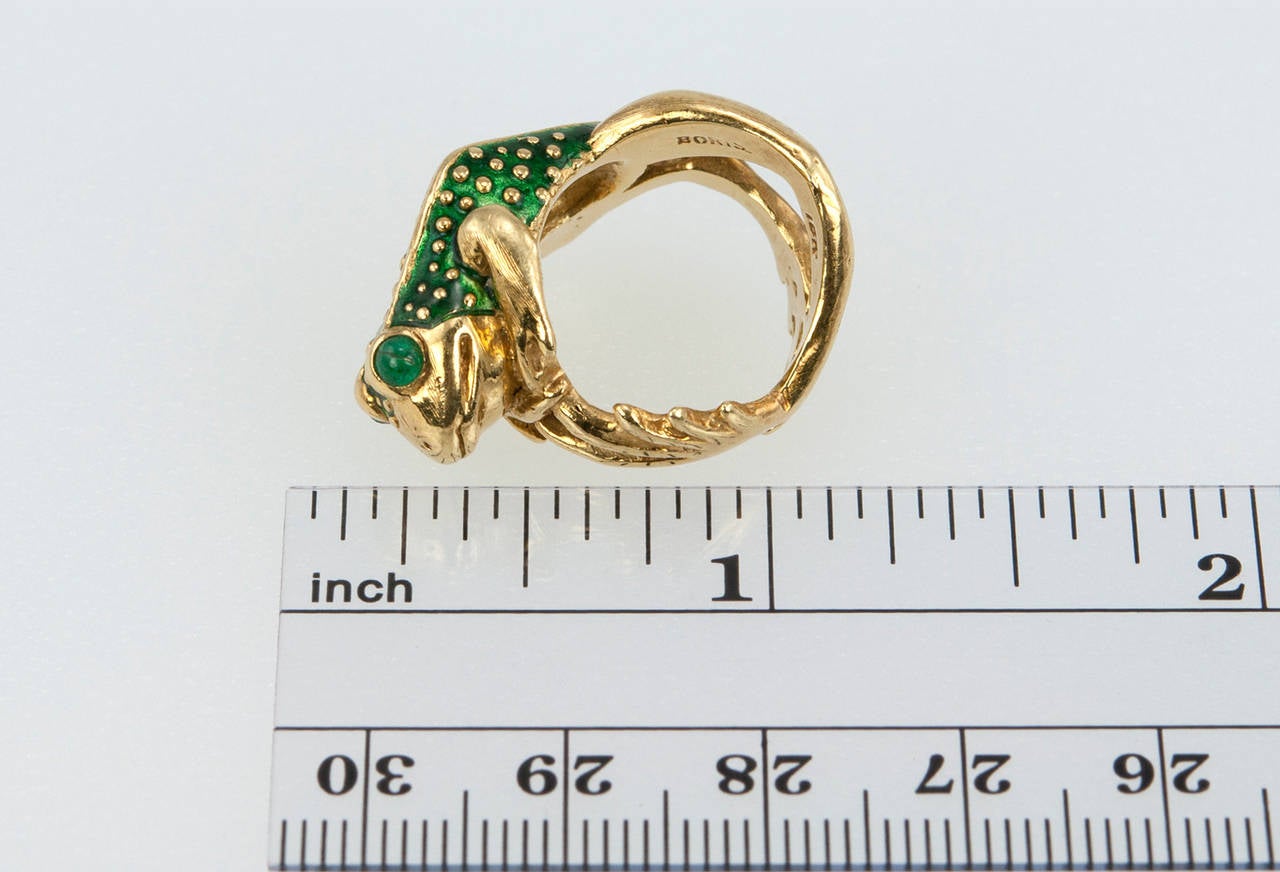 A quirky and whimsical Boris LeBeau green enameled frog ring with cabochon emerald eyes in 18 karat yellow gold. Circa 2000s. 

Currently a US size 4.