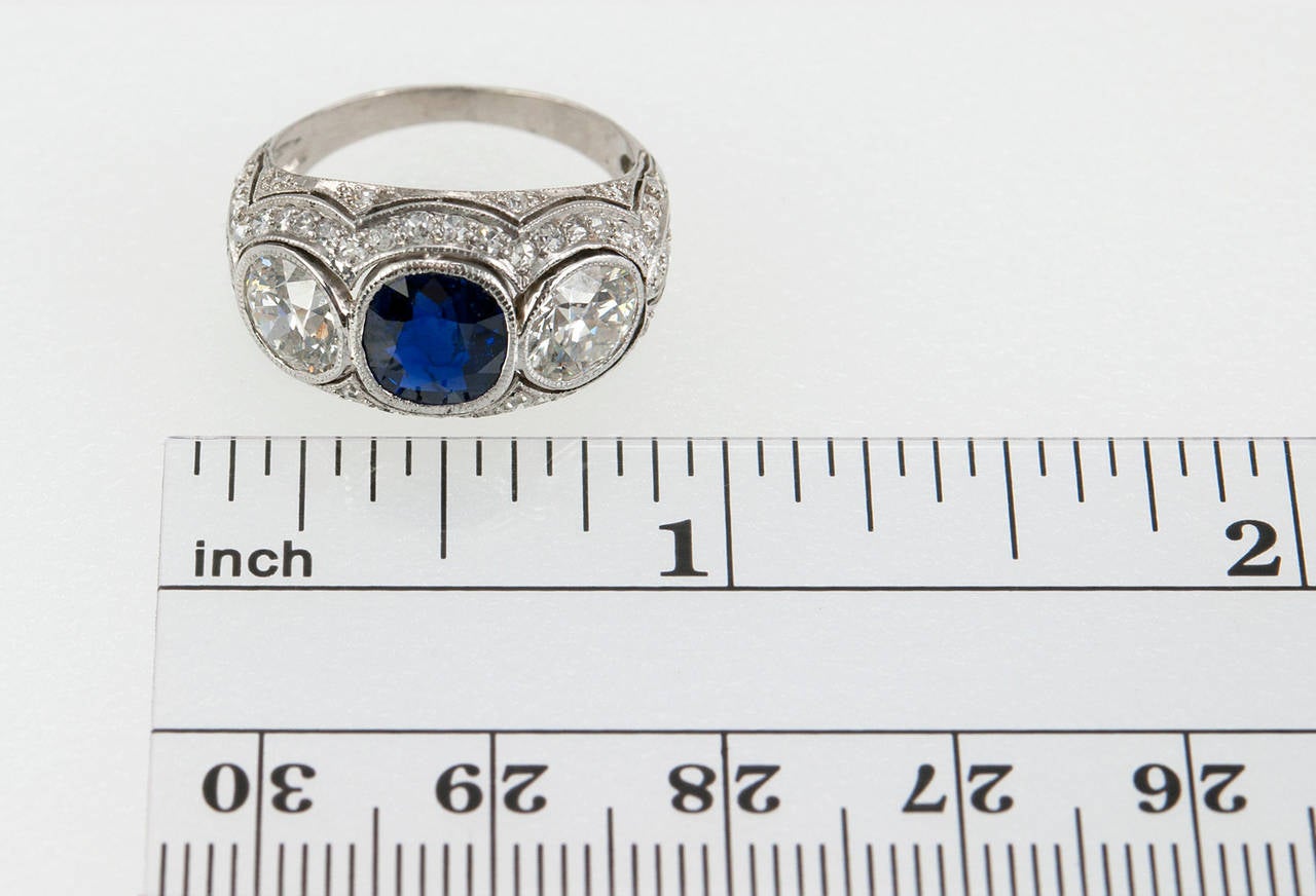 This gorgeous Art Deco three-stone platinum ring features a natural, no heat cushion cut sapphire (AGL), approximately 1.30 carats, in the center along with two bright, beautiful transitional cut diamonds; a 0.89 carat G-VS1 and 0.91 carat H-VS1