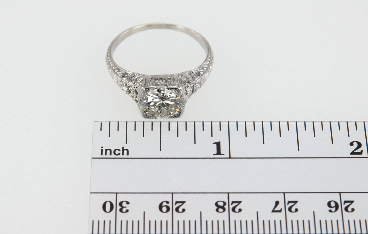 This beautiful Edwardian platinum engagement ring features a 1.52 carat I-SI1 (EGL) Old European Cut diamond set in a square mounting with fine milgraining and accented by four small round diamonds and pierced open work throughout. This ring also