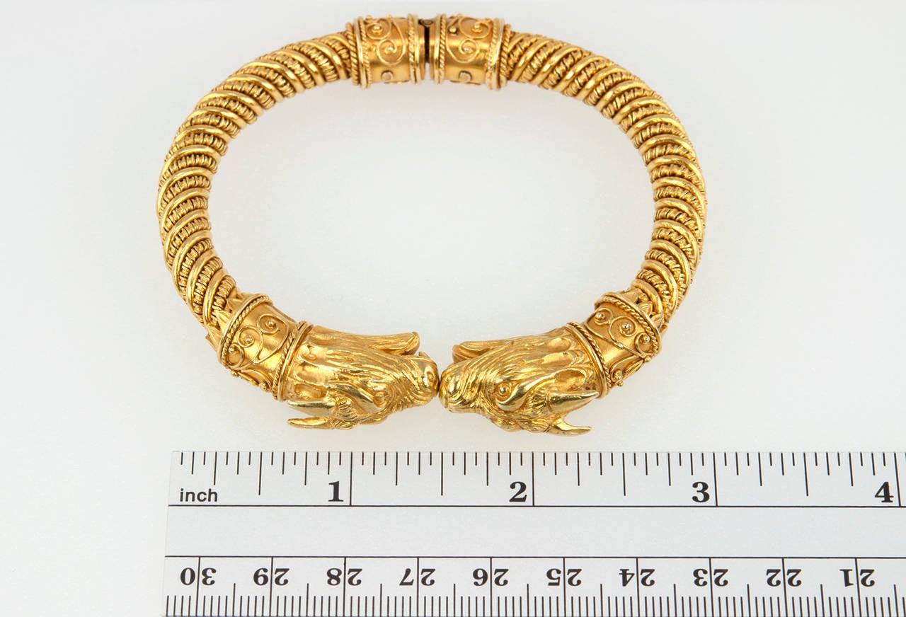 An Etruscan revival style hinged bracelet with a double-headed mythological creature at the opening in 18 karat yellow gold. The bracelet is marked 