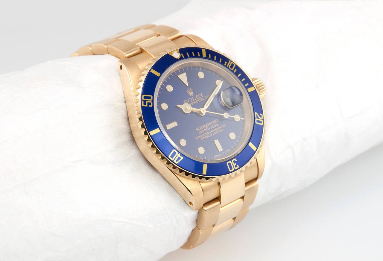 Rolex Submariner wristwatch in 18 karat yellow gold, reference 16618. This beautiful 1992 classic blue submariner features a sapphire crystal, locking waterproof gold crown, blue dial and blue bezel. The watch is on a 18K oyster band with flip lock