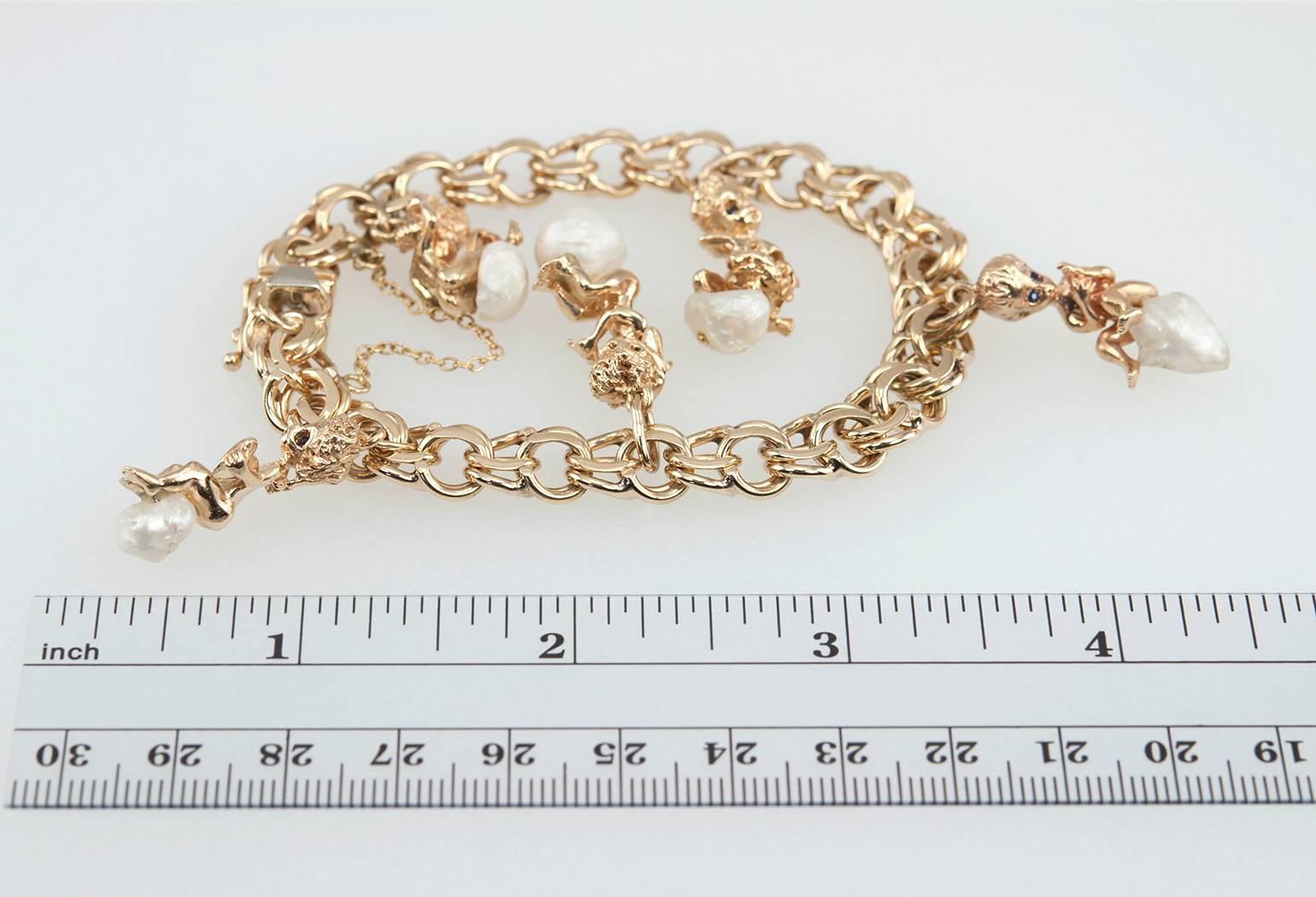 A Ruser 14 karat yellow gold charm bracelet.  This link bracelet features 5 charms that dangle from the bracelet with Ruser's babies that have sapphire eyes sitting on pearls.  Circa 1970s.

The bracelet is approximately 7 inches in diameter. The