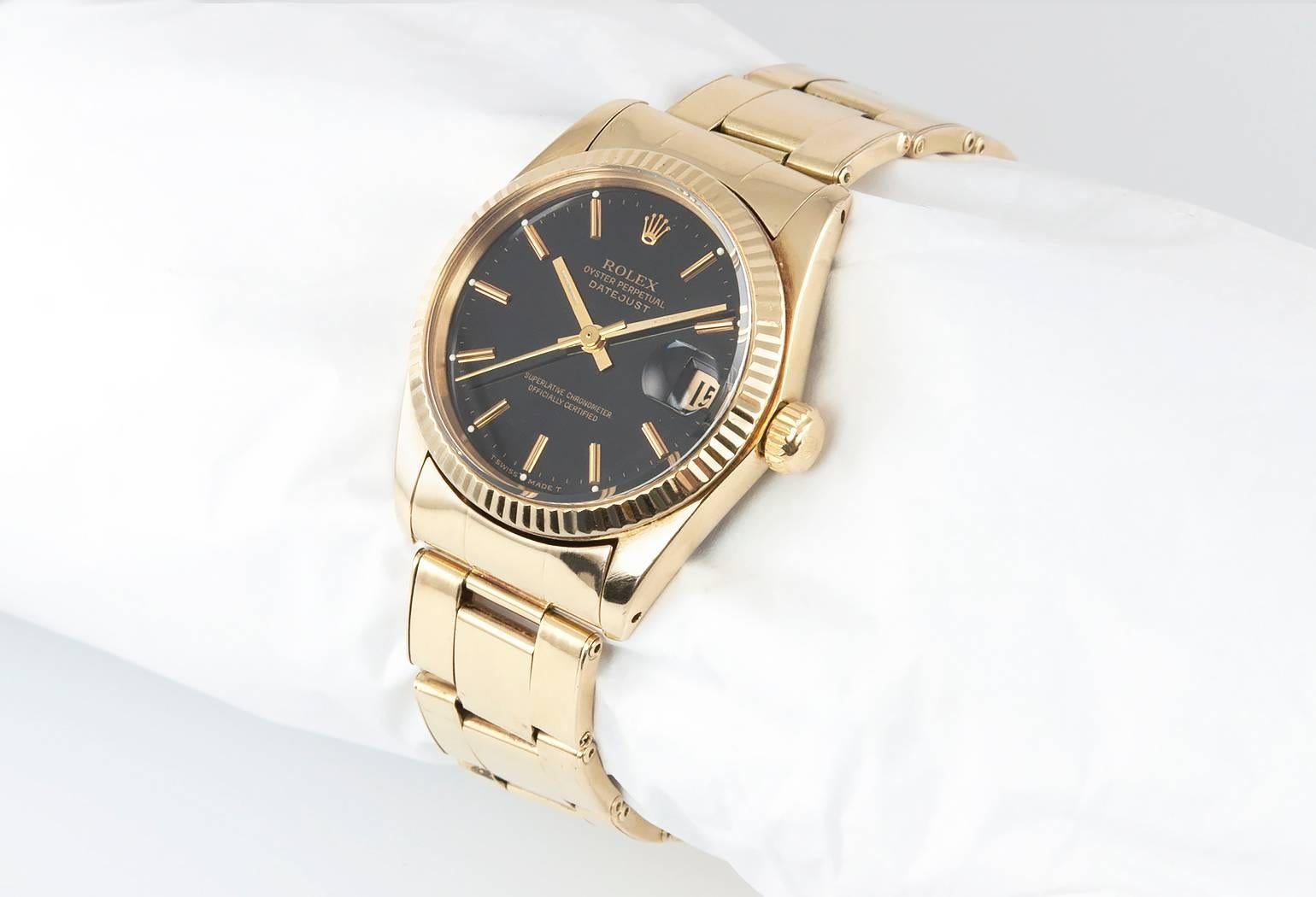 Rolex DateJust wristwatch in 14 karat yellow gold, reference 6827.  This classic Rolex features a 14 karat yellow gold case, a riveted oyster band, fluted gold bezel, a black original dial with stick markers, plastic crystal, locking waterproof
