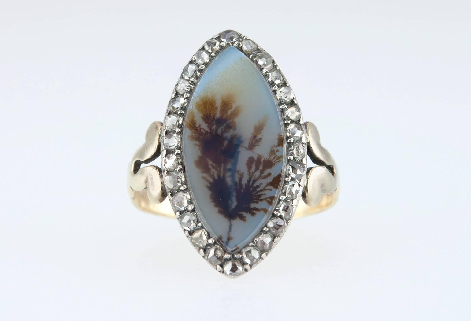 A beautiful and rare antique Georgian ring from circa 1780s. The navette shaped ring features a piece moss agate with 28 rose cut diamonds surrounding the 14 karat yellow gold and silver topped ring.  A lovely floral abstract pattern is engraved on