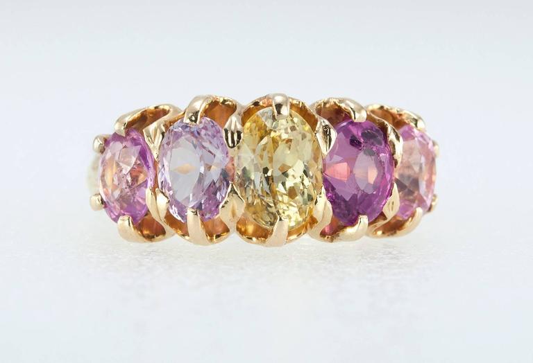 F. Walter Lawrence natural sapphire five stone ring in 18 karat yellow gold.  This gorgeous ring features a light pink sapphire, a dark pink sapphire, a yellow sapphire, and 2 more light pink sapphires set in a shared-prong claw setting.  The colors
